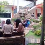 Para pelajar SMP Negeri 1 Kota Mojokerto sedang asyik baca buku perpustakaan di Taman Sekolah.