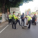 Petugas Satlantas Polresta Sidoarjo sedang mengamankan ban-ban yang dipakai tanda mobil boks sedang mogok.