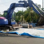 Alat berat backhoe saat memusnahkan ribuan liter miras di halaman Mapolres Tuban.