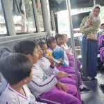 Seorang Mahasiswi Uniska saat memandu anak-anak di dalam Bis Satria. (Ist)