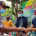 Ketua Kelompok Tani Mugi Rahayu Desa Tiru Kidul, Kabupaten Kediri, Sukarno, menyerahkan potongan nasi tumpeng kepada Sekretaris Dispertabun Kabupaten Kediri, Triyono. foto: MUJI HARJITA/ BANGSAONLINE