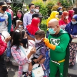 New Man sedang memberikan sekaligus memakaikan masker ke pengunjung anak-anak yang tidak memakai masker di KBS. foto: YUDI A/ HARIAN BANGSA