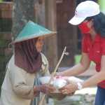 Nuri Yunita Sari saat membagikan beras kepada salah satu lansia di Desa Ngares Kecamatan Trenggalek. foto: HERMAN/ BANGSAONLINE