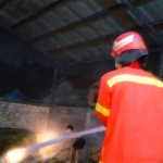 Petugas Damkar Gresik saat melakukan pemadaman gudang kertas yang terbakar. Foto: SYUHUD/ BANGSAONLINE