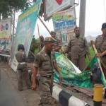 DITURUNKAN – Petugas Satpol PP Trenggalek saat menertibkan papan reklame yang melanggar aturan, di Jalan Soekarno – Hatta, Trenggalek, Kamis (30/7). foto: herman/BANGSAONLINE