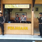  Petugas kepolisian berpakaian lengkap dengan rompi anti peluru, helm, dan senjata laras panjang siaga di depan gerbang markas Polres Blitar Kota.