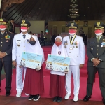 Bupati Pamekasan, Baddrut Tamam, saat memberi penghargaan kepada dua murid SD yang memperoleh perak di tingkat nasional.