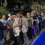 Seorang petugas membagikan sedekah Prof Dr KH Asep Saifuddin Chalim, MA di depan Pondok Pesantren Amanatul Ummah Jalan Siwalankerto Utara Surabaya, Rabu (6/5/2026) malam. Foto: MMA/bangsaonline