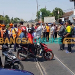 Petugas dari KAI saat memberikan sosialisasi kepada pengguna jalan di perlintasan kereta api sebidang. Foto: BANGSAONLINE