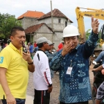 Bupati Sambari HR didampingi Kadishub Andhy Hendro Wijaya saat mengatur lalu lintas jalan Sembayat yang macet akibat terendam banjir. foto: SYUHUD/ BANGSAONLINE