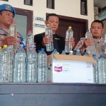 Petugas Polsek Ngancar saat menunjukkan barang bukti berupa 35 botol miras jenis arak jowo. Foto: Ist.