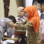 Gubernur Khofifah Indar Parawansa didampingi Ketua KPU Jatim Choirul Anam menyerahkan santunan kepada keluarga petugas penyelenggara pemilu yang wafat saat menjalankan tugas pada Pemilu 17 April. foto: ist