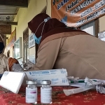 Yeni, Bidan Desa Kambingan, Kecamatan Pagu, Kabupaten Kediri saat menyuntikkan Vaksin AstraZeneca kepada salah satu lansia di Balai Desa Kambingan, Kamis (1/4/2021). (foto: MUJI HARJITA/BANGSAONLINE)