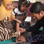 Wali Kota Kediri, Abdullah Abu Bakar, saat memakaikan sepatu ankle foot orthosis (AFO) di kaki Erika Adinia Putri. Foto: Ist