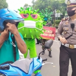 Kasatlantas Polres Jombang bersama badut Corona saat memberhentikan pengendara yang tak pakai masker. foto: AAN AMRULLOH/ BANGSAONLINE