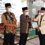 Ketua DMI Zainal Abidin menyerahkan piagam kepada Imam Basuki selaku perwakilan DPUTR Gresik dalam program sumur masjid. foto: SYUHUD/ BANGSAONLINE