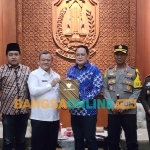 Pj. Gubernur Jawa Timur Adhy Karyono menyerahkan Surat Keputusan (SK) perpanjangan jabatan Pj Bupati Sampang kepada Rudi Arifiyanto. Foto: Devi Fitri Afriyanti/BANGSAONLINE