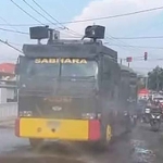 Petugas Satsamapta Polres Gresik dengan mobil water cannon menyemprot jalan yang berdebu di ruas Jalan Yosowilangun-Suci. Foto: Ist