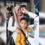 Tim Medis mengecek suhu setiap penumpang kereta api di Stasiun Madiun.