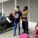 Petugas saat memasangkan masker kepada warga yang terjaring operasi yustisi. (foto: ist.)
