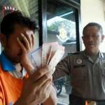 PENGECER: Tersangka Suroto Ady Wijaya menutupi wajahnya sambil menunjukkan barang bukti (BB) uang yang diterima dari menjadi pengecer togel, kemarin. foto: catur andy erlambang/BANGSAONLINE