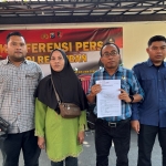 Suning bersama kuasa hukumnya Nur Azis (tengah) usai melaporkan oknum perangkat desa yang lakukan arogansi dan penyerobotan lahan. Foto: Suwandi/BANGSAONLINE