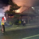 Petugas mengamankan lokasi di sekitar warung sate milik Turmudi yang terbakar.