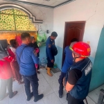 Anggota Damkar Gresik saat akan membuka paksa kamar kos yang terkunci dari dalam