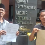 Kustiono (kiri) menunjukkan tanda terima laporan ke Polda Jatim.