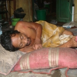 Sudaryono, lelaki sebatang kara yang mengalami kelumpuhan terbaring di ruang tamu rumahnya hanya beralaskan tikar kasar. Foto: SYUHUD A/BANGSAONLINE