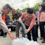 Bupati Mojokerto Muhammad Albarra saat menyalurkan air bersih ke jeriken milik warga.