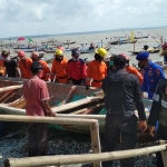 Petugas Ditpolair Polda Jatim bersama warga setempat saat mengevakuasi salah satu perahu nelayan.