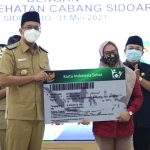 SIMBOLIS: Bupati Ahmad Muhdlor menyerahkan replika kartu peserta BPJS Kesehatan saat MoU UHC, di Pendapa Delta Wibawa, Senin (31/5/2021). foto: istimewa