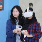 Mahasiswi ITS (kiri) sedang memandu siswi SMPN 32 Surabaya saat mencoba menggunakan RRekon VR. (Ist)