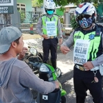 Petugas Satlantas Polres Batu sedang memberikan edukasi kepada salah satu pengendara yang tidak memakai helm dan masker.