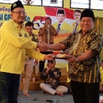 Ketua Golkar Gresik, Ahmad Nurhamin menyerahkan potongan tumpeng pada Bendahara Nasdem Tri Putro Utomo. foto: SYUHUD/ BANGSAONLINE