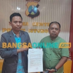 Tim kuasa hukum DPC Demokrat Situbondo, Dwi Anggi Septiawan dan Budi Irawanto saat menunjukkan laporan ke polisi. Foto: SYAIFUL BAHRI/BANGSAONLINE