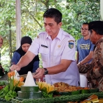 Plt. Kepala Dinas Pariwisata dan Kebudayaan Kabupaten Kediri, Mustika Adi Prayitno, saat memotong tumpeng yang menandai dibukanya kembali Wisata Sumber Ubalan. Foto: Ist.