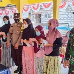 Kades Morobakung Muhammad Askur Farid (paling kiri) bersama babinsa dan bhabinkamtibmas saat menyerahkan bantuan. (foto: SYUHUD/BANGSAONLINE)