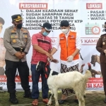 Bupati Arifin sedang menunjukkan hadiah ternak kambing bagi warganya yang mengikuti vaksinasi massal.