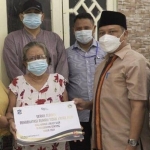 Kepala Dinas Sosial (Dinsos) Kota Surabaya, Suharto Wardoyo saat menyerahkan bantuan kepada salah satu lansia penerima manfaat program rehabilitasi rutilahu, Kamis (24/6/2021).