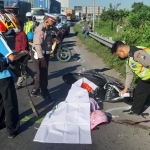 Petugas melakukan olah TKP di lokasi kejadian. Tampak jasad korban ditutupi terpal.