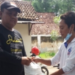 Salah satu relawan PKB Situbondo saat menyerahkan nasi bungkus kepada salah satu korban puting beliung. 