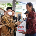 Kepala DKP Gresik, Mohamad Nadlelah didampingi Kades Sukorejo Fatkhur Rohman menyerahkan bantuan kepada melayani. Foto: SYUHUD/BANGSAONLINE.com