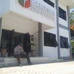 Seorang polisi berjaga sambil duduk di pintu masuk kantor Bawaslu Surabaya. 