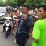 Tersangka Agus saat diamankan petugas Polsek Kebomas dari amukan massa. Foto: SYUHUD A/BANGSAONLINE