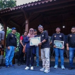 Ketua panitia HPN KWG 2025, Khanif Rosidin, saat memberikan piagam penghargaan kepada perwakilan Freeport Indonesia dalam Festival Nasi Krawu 2025 di Wagos. Foto: Ist