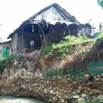 Rumah warga yang berada di dekat tebing sungai rusak akibat tergerus air saat hujan deras. foto: RONY S/BANGSAONLINE
