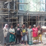 Beberapa warga tampak foto di depan proyek pembangunan kantor pelayanan kesehatan.