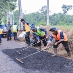 Petugas saat memperbaiki jalan rusak di Jember.